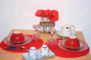 une table avec des assiettes et des fleurs rouges et blanches à la polka dans l'établissement Le studio de Manoline, à Bourges