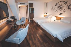 a hotel room with two beds and a desk and chairs at Hotel Bernina Geneva in Geneva