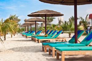 Sahara Beach Resort & Spa في الشارقة: صف من كراسي الشاطئ والمظلات على الشاطئ