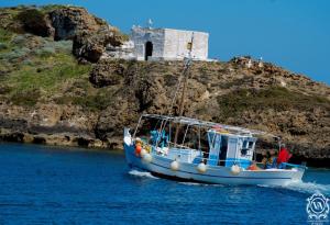 a blue boat in the water with a castle in the background at Studio Cozy - In the Heart of Skyros Village in Skiros