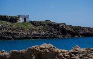 a building on a hill next to a body of water at Studio Cozy - In the Heart of Skyros Village in Skiros