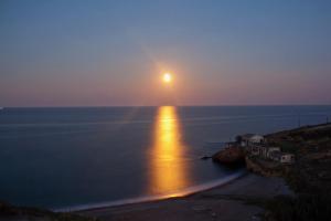 a sunset over the ocean with the sun setting on the water at Studio Cozy - In the Heart of Skyros Village in Skiros