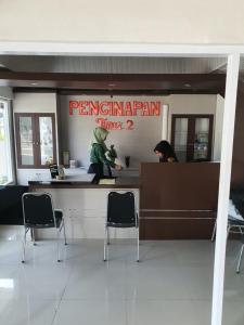 RedDoorz near Palembang Airport 2 في باليمبانغ: مطعم فيه كرسيين وكاونتر في مبنى