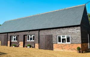 a barn with a gray roof and white windows at Bluebell Cottage at The Old Tractor Barn in Brackley