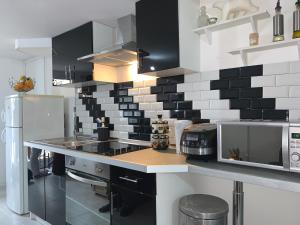 a kitchen with black and white tiles on the wall at Logement cosy proche Paris et Disneyland in Villiers-sur-Marne