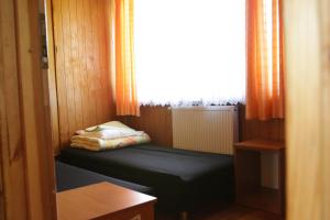 um pequeno quarto com uma cama num quarto com uma janela em Camping Oaza Błonie Kórnik Domki Standard - 3 pokoje em Kórnik