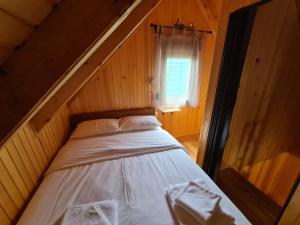 a bed in a wooden room with a window at Black Pine in Žabljak