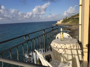 a table with a bottle of wine on a balcony overlooking the ocean at La Casa Sulla Scogliera in Cefalù
