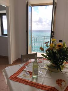 a table with wine glasses and a view of the ocean at La Casa Sulla Scogliera in Cefalù