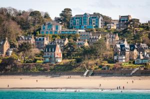 a group of people on a beach with houses at L'Agapa Hôtel - Spa Codage in Perros-Guirec