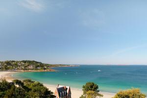 a view of a beach with a house and the ocean at L'Agapa Hôtel - Spa Codage in Perros-Guirec