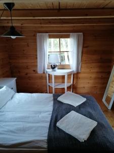 a bedroom with a bed with a table and a window at Hannuksen Piilopirtti in Tyrnävä