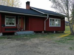 a red house with a chair on the front porch at Hannuksen Piilopirtti in Tyrnävä