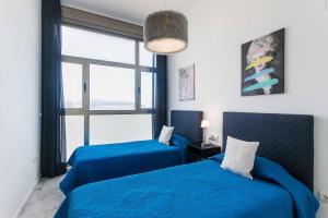 2 camas azules en una habitación con ventana en 42nd floor - Penthouse VIP with private terrace and sea views, en Benidorm