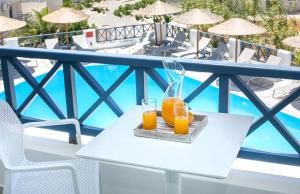 two glasses of orange juice on a table on a balcony at Hotel Sunshine in Kamari