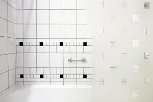 a bathroom with a shower with black and white tiles at L'Agapa Hôtel - Spa Codage in Perros-Guirec