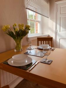 a table with plates and glasses and a vase of flowers at The Stables Apartment in Newark-on-Trent
