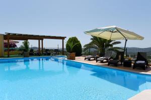 a swimming pool with chairs and an umbrella at Hotel Rural Rocha da Gralheira in São Brás de Alportel