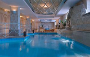 a large swimming pool with blue water in a building at Miramare E Castello in Ischia