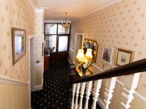 a hallway with a staircase with a mirror and a lamp at Crescent Lodge Guest House in Whitby