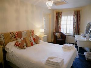 a hotel room with a bed, chair, and nightstand at The White Hart in Whitchurch