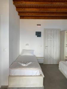 a white bedroom with a bed and a wooden ceiling at Studios Betty in Plaka Milou