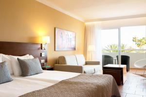ein Hotelzimmer mit einem Bett und einem Stuhl in der Unterkunft Sunprime Atlantic View Suite & Spa in Playa del Ingles