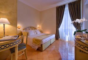 a hotel room with a bed and a desk and a window at Miramare E Castello in Ischia