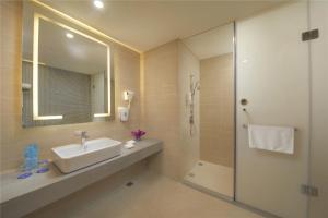 uma casa de banho com um lavatório e um chuveiro com um espelho. em Holiday Inn Express Zhengzhou Zhengdong, an IHG Hotel em Zhengzhou