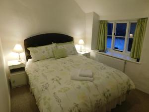 a bedroom with a large bed and two windows at Middletown Farmhouse B&B in Okehampton