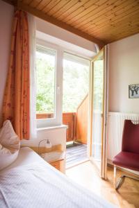 ein Schlafzimmer mit einem Bett, einem Fenster und einem Stuhl in der Unterkunft Pension Hartmann in Sankt Kanzian am Klopeiner See