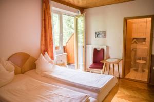 1 dormitorio con cama, ventana y silla en Pension Hartmann en Sankt Kanzian