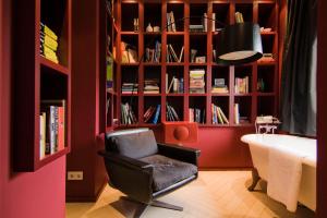 ein Zimmer mit einem Stuhl und einem Bücherregal mit Büchern in der Unterkunft Teaching Hotel in Maastricht