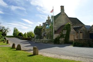 伯福德The Swan Inn Swinbrook的道路一侧有旗帜的建筑物