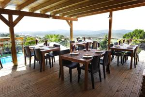 un restaurante con mesas de madera y sillas en una terraza en Hotel Rural Rocha da Gralheira, en São Brás de Alportel