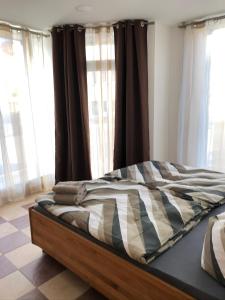 een bed in een kamer met ramen en gordijnen bij KL17 Ostel Döbeln in Döbeln