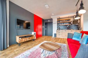 a living room with a red couch and a table at Apartamenty Sun & Snow Chmielna Park in Gdańsk