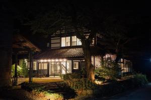 un bâtiment avec un arbre devant lui la nuit dans l'établissement Takigahara Craft & Stay, à Komatsu