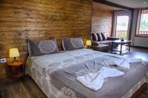 1 dormitorio con 1 cama grande y pared de madera en Medi Guest House, en Sapareva Banya