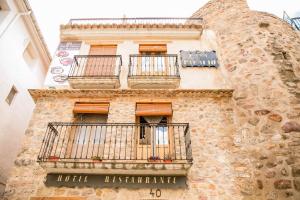 un edificio de piedra con balcones y una señal en él en Hotel Casa Palacio, en Montanejos