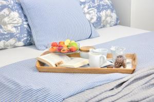 a tray with a bowl of fruit and a plate of food on a bed at Dida moj in Senj