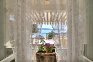 a window with white curtains and a basket with plants at Dida moj in Senj