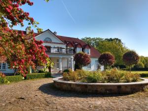 a large white house with a garden in front of it at Dwór w Bychowie in Bychowo