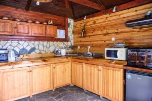 cocina con armarios de madera, fregadero y microondas en Medi Guest House en Sapareva Banya