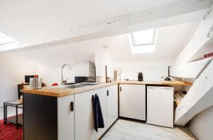 una cocina en el ático con armarios blancos y fregadero en Le Cocon - Chaleureux Studio Centre Ville au Calme, en Toulouse 9 fotos más