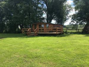 a wooden cabin in a field with a tree at Old Mill House Log Cabins in Dorchester