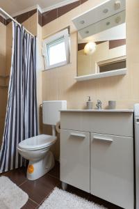 une salle de bains avec toilettes, lavabo et miroir dans l'établissement Apartments Elita, à Rovinj