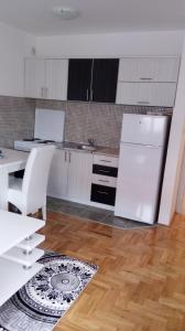 a kitchen with a white refrigerator and a wooden floor at Apartman Sanja in Lukavica