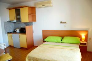 a bedroom with a bed with green pillows and a kitchen at Studio Ante in Brela
