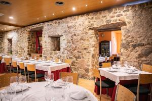 a restaurant with white tables and chairs and stone walls at Hotel El Palacio de Montanejos in Montanejos